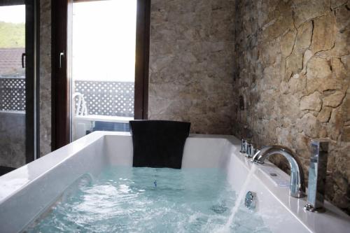 a bath tub with a chair sitting in the water at Casa Rural Casa de Chocolate in Cuevas del Valle