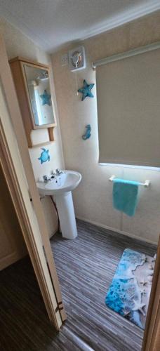 a bathroom with a sink and a toilet and a mirror at KC Caravan Hire in Kinmel Bay