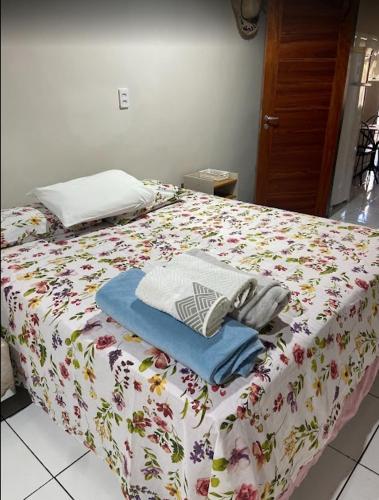 a bed with a flowered sheets and towels on it at Kitnet com quarto amplo e cozinha Santarém- Pará in Santarém