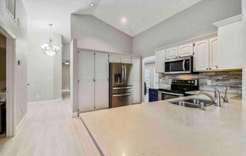 a kitchen with white cabinets and a stainless steel refrigerator at Florida house, 4br 2bt with private pool oasis in Naples