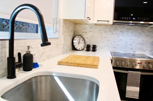 a kitchen with a sink and a clock on the wall at 2BDR Stylish Comfort Parkside in Vancouver