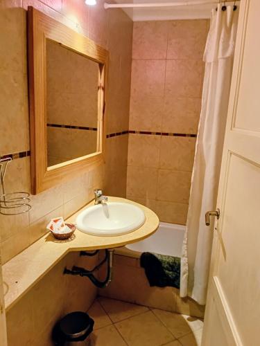 a bathroom with a sink and a mirror and a tub at Hostal del Sur in Mar del Plata