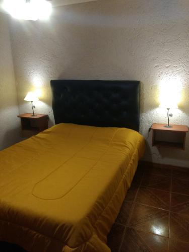 a bedroom with a yellow bed with two lamps at Tierra Nuestra in Villa Ciudad de América