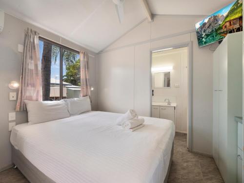 a bedroom with a large white bed with a window at BIG4 Townsville Gateway Holiday Park in Townsville