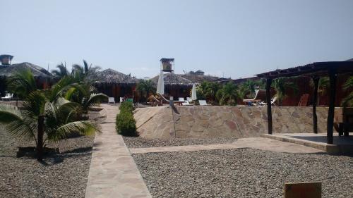a resort with a stone wall and a palm tree at Guille Bungalows in Canoas De Punta Sal