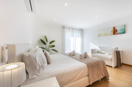 a white bedroom with a large bed and a chair at Infinity Penthouse in Lagos