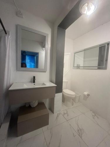 a white bathroom with a sink and a toilet at Vieques Good Vibe Guest House in Vieques