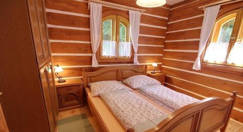 a small bedroom with a bed and two windows at Chalupa Žernovka in Žernov