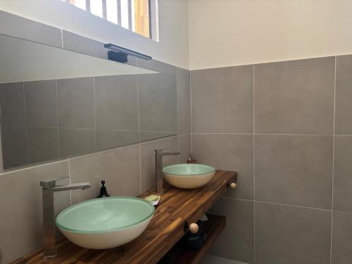 two sinks on a wooden counter in a bathroom at Villa exceptionnelle en bord de mer - SUNSET VILLA in Pointe-Noire