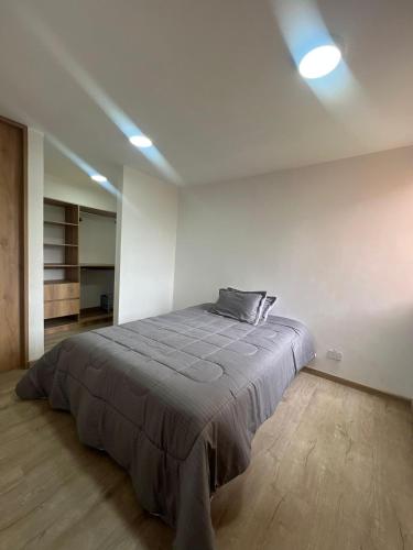 a bedroom with a large bed in a white room at Apartamento familiar de 3 habitaciones con parqueadero en Paipa in Paipa