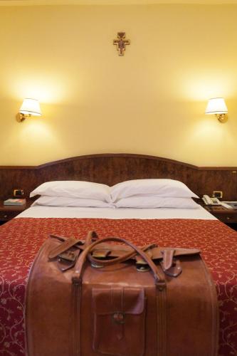 a brown suitcase sitting on top of a bed at Hotel Villa Elda in Assisi