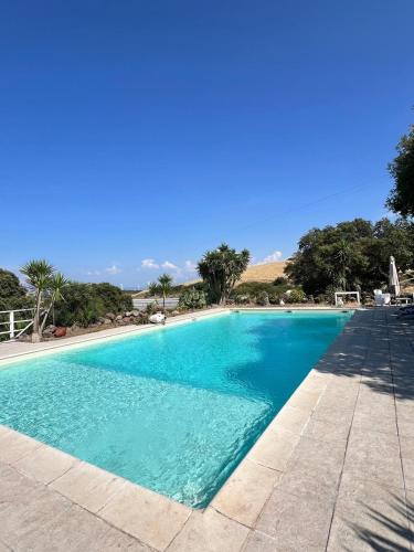 a large blue swimming pool with trees in the background at Il Lentischio Casa1 in Nulvi