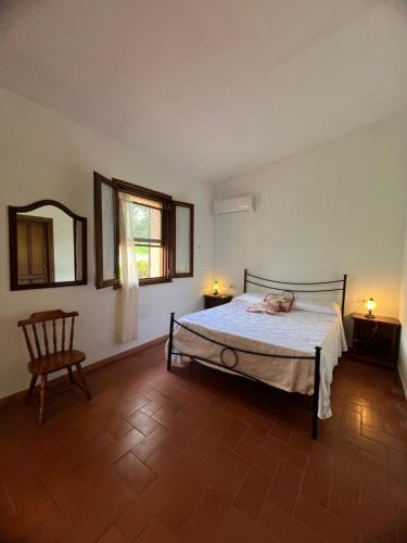 a bedroom with a bed and a chair and a mirror at Il Lentischio Casa1 in Nulvi