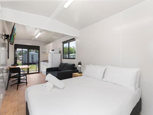 a bedroom with a white bed and a living room at BIG4 Townsville Gateway Holiday Park in Townsville