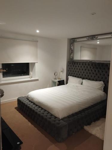 a bedroom with a large bed with a black headboard at 2 Bedroom APARTMENT in Manchester