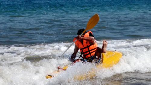 a man riding a yellow kayak in the ocean at Guille Bungalows in Canoas De Punta Sal