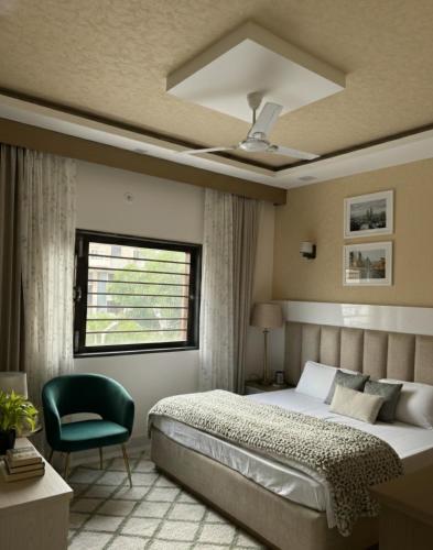 a bedroom with a bed and a chair and a window at Hotel Nirmal Bhawan Haridwar in Haridwār