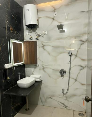 a bathroom with a sink and a shower stall at Hotel Nirmal Bhawan Haridwar in Haridwār
