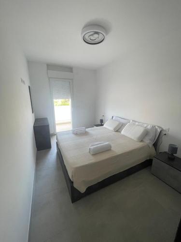 a white bedroom with a large bed and a window at Brezza Marina - Vacation Condo in Marina di Vasto