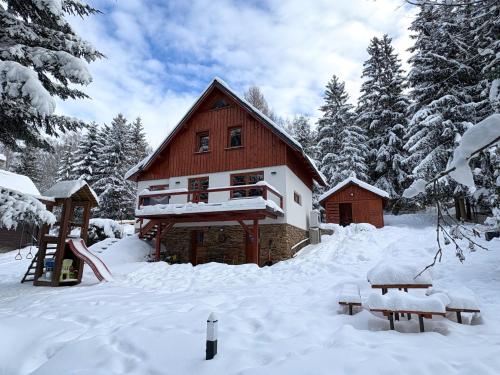 a log cabin in the snow with a playground at Horská chata Poustka in Benecko