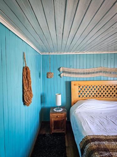 a bedroom with a blue wall with a bed and a table at Casa Chiloe hostel in Castro