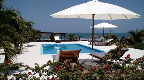 una piscina con sombrilla, sillas, mesa y sombrilla en Guille Bungalows, en Canoas de Punta Sal