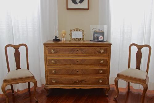 a dresser with a radio and two chairs at Casa Côrte Real in Porto