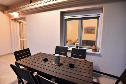 a dining room with a wooden table and a window at Adams Suites in Paleo Tsifliki
