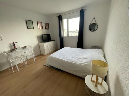 a bedroom with a bed and a table and a window at Calais plage, superbe studio tout confort in Calais