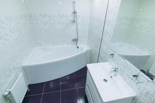 a white bathroom with a tub and a sink at Apart Lawina in Sumy