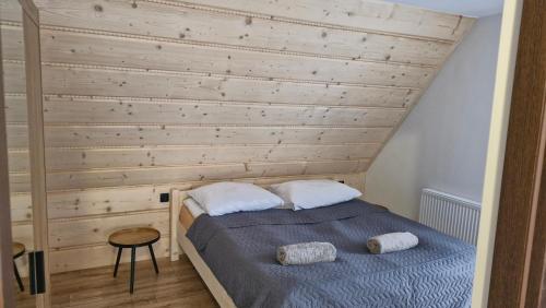a bedroom with a wooden wall and a bed with two pillows at Chochołowsko-Witowski Wypoczynek in Witów
