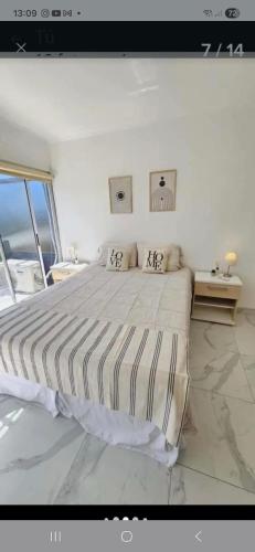 a white bedroom with a large bed and a window at Apartamentos del campus in Presidente Derqui