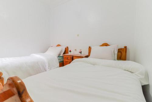 three beds in a room with white sheets at Appartement calme et ensoleillé avec WiFi haut débit in Sidi Ifni