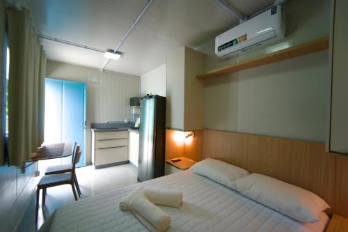 a bedroom with a large white bed and a desk at Villammare Cachoeira in Florianópolis