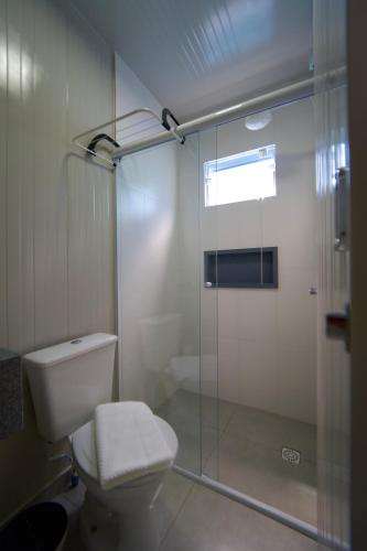 a bathroom with a toilet and a glass shower at Villammare Cachoeira in Florianópolis