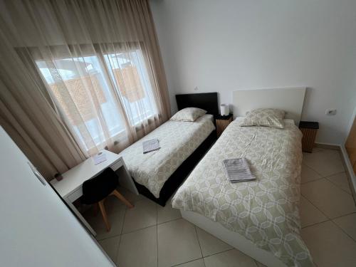two beds in a small room with a window at Beachfront Apartment in Assilah, Private Solarium, 4 Pools, Secure Residence, WiFi, Parking in Asilah