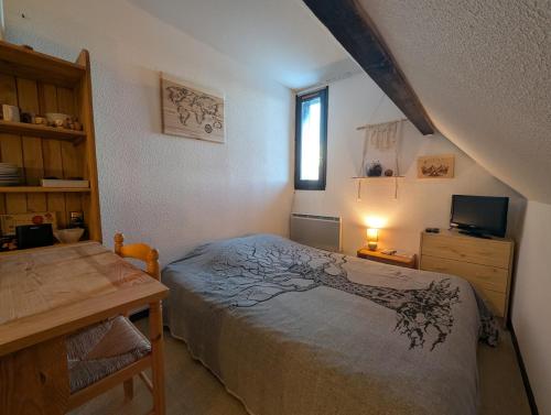 a bedroom with a bed and a desk and a window at Studio pied des pistes in Réallon