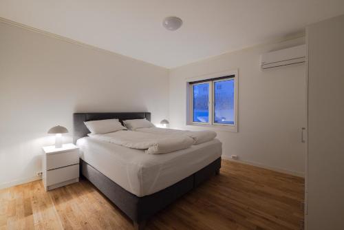a white bedroom with a large bed and a window at Fauske Central Apartment - Cozy & Walkable in Fauske