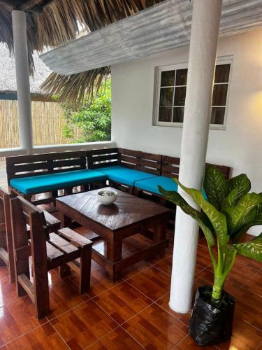 a room with a wooden table and bench and a palm tree at Backpackers Hostel in El Paredón Buena Vista