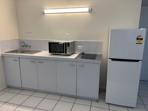 a kitchen with a microwave and a refrigerator at Shakespeare Motel in Mackay