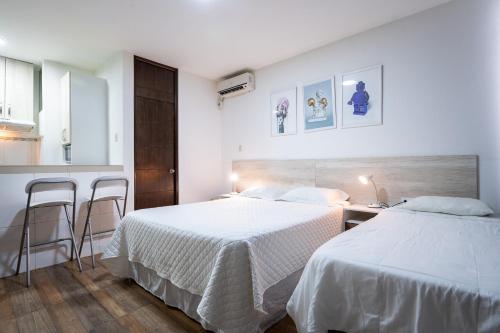 Zwei Betten in einem Schlafzimmer mit weißen Wänden und Holzböden in der Unterkunft Studio rent in Piura