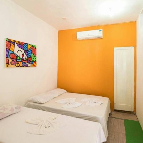 two beds in a room with a painting on the wall at Pousada Maresia in Fortaleza