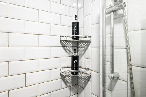 a shower with two baskets on a white tiled wall at Beautiful Modern Apartment on Wick Lane in London