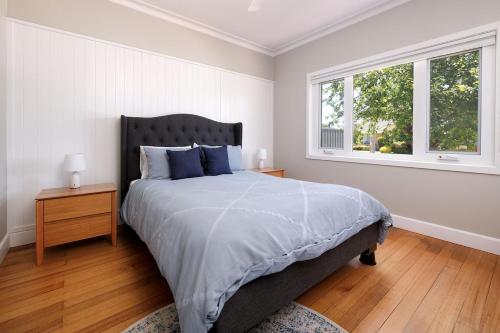 a bedroom with a large bed and two windows at Cute Cummings St Cottage in Wodonga