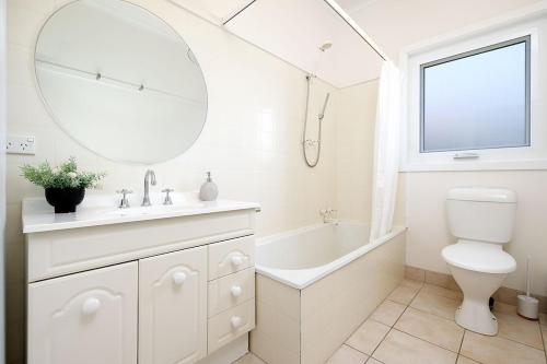 a bathroom with a sink toilet and a mirror at Cute Cummings St Cottage in Wodonga