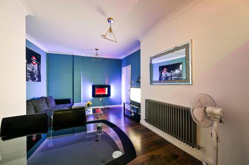 a living room with blue walls and a glass table at Beautiful Modern Apartment on Wick Lane in London
