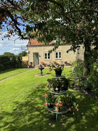 a house with a garden with flowers in a yard at Cosy Flint Cottage in Thurston