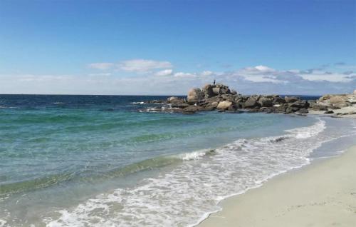 a beach with a person standing on a pile of rocks at La Tanière in Rosporden