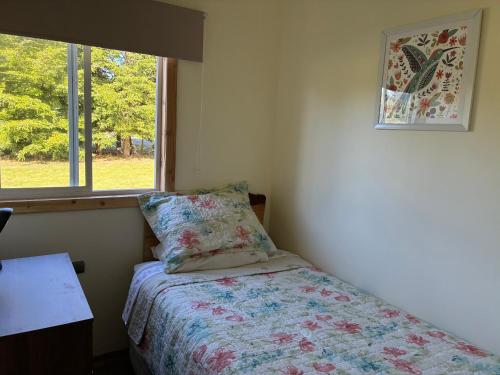 a bedroom with a bed with a pillow and a window at Cabaña de Lujo Independiente in Frutillar