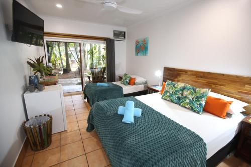 a bedroom with a bed with a blue cross on it at Rainforest Motel, Mission Beach in Mission Beach